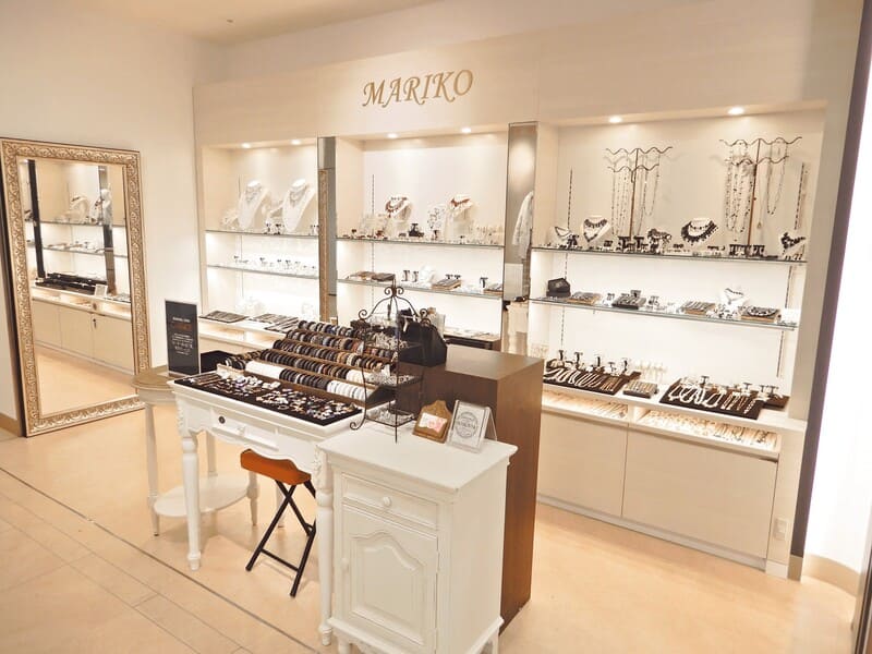 ブライダルアクセサリー マリコの店舗内観。MARIKOのロゴが入った白を基調とした上品な店内に、ティアラ・ネックレス・イヤリング・ブレスレットなど豊富なブライダルアクセサリーが並んでいる。