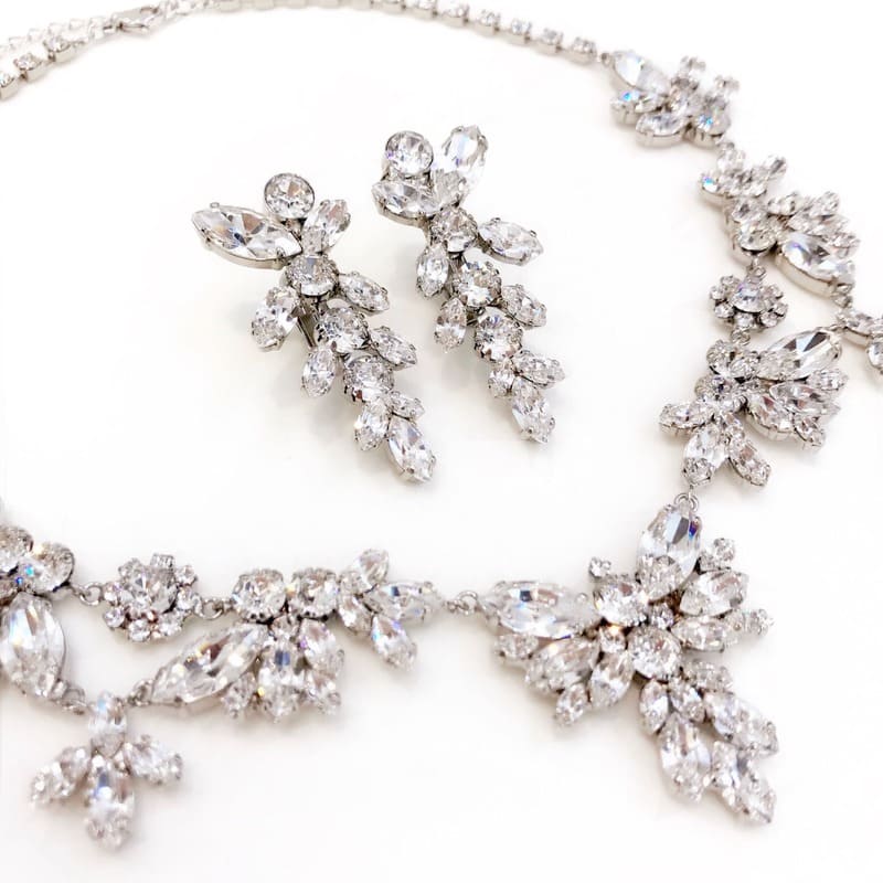 本ロジウムコーティングによるブライダルネックレスとイヤリングのセット。マリコの高品質メッキ加工により、クリスタルを取り巻く金属部分が美しく輝いている。